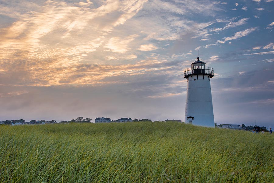 Marshfield, MA Insurance - White Lighthouse Standing in a Grassy Dune at Dusk